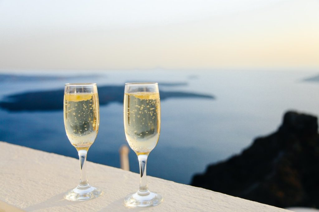 two champagne glasses on balustrade overlooking blue sea